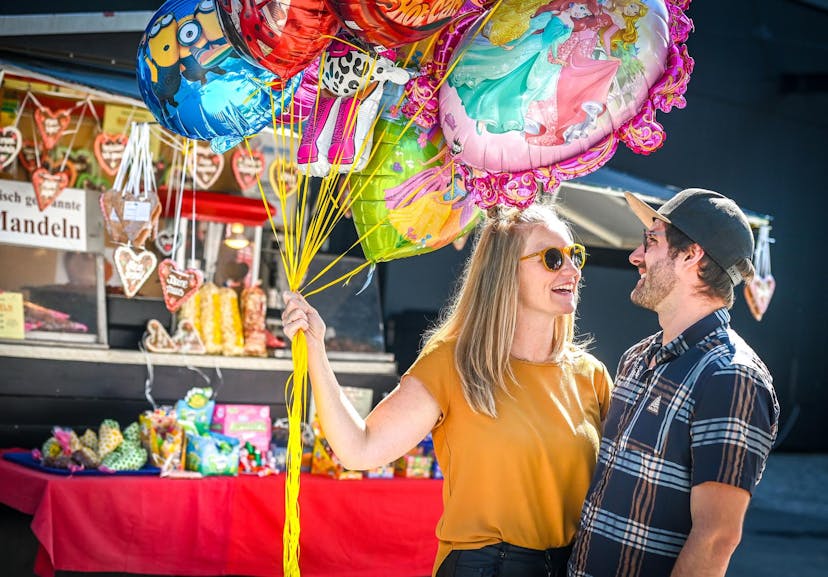 Paar mit Luftballons im Freigelände der Herbstmesse. © Udo Mittelberger